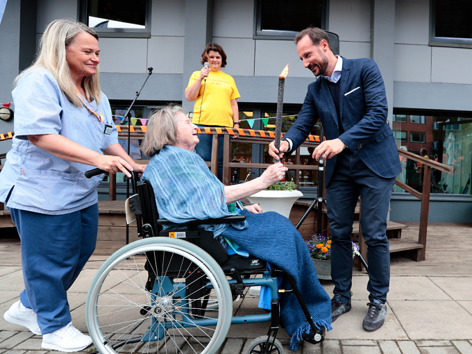 Kronprins Haakon mottar fakkelen fra 102 år gamle Ingrid Lundal, før han tenner ilden og åpner Sofienberglekene. Foto: Lise Åserud / NTB scanpix